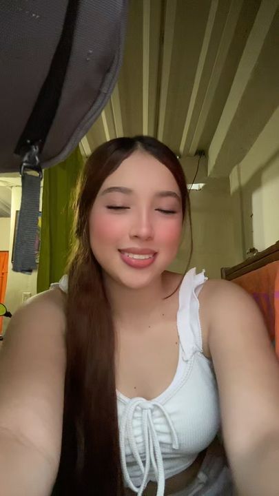A woman with long hair laughing during a live video chat