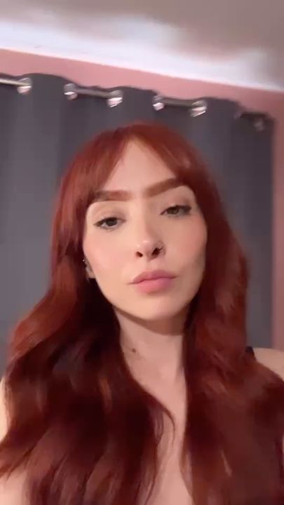 A woman with red hair talking to her camera