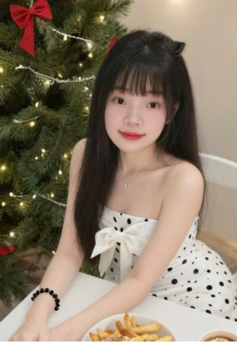 A woman in a polka dot dress smiling beside a Christmas tree