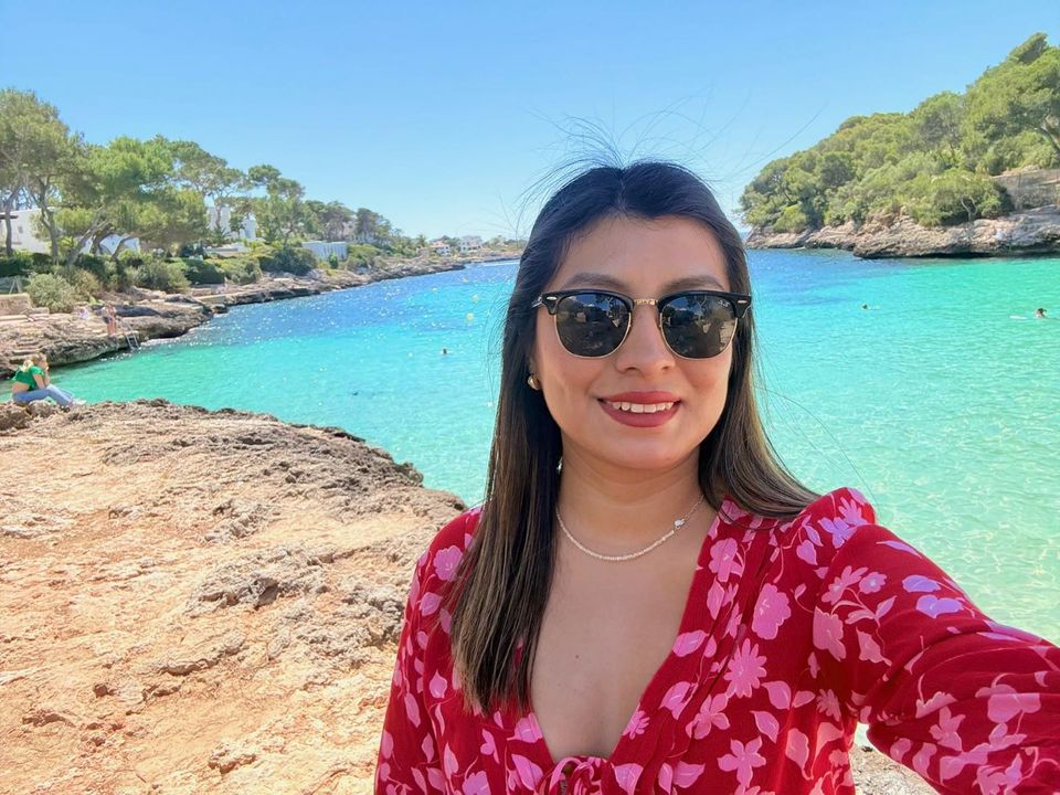 Smiling woman in sunglasses on a coastline, relaxed during safe video chat